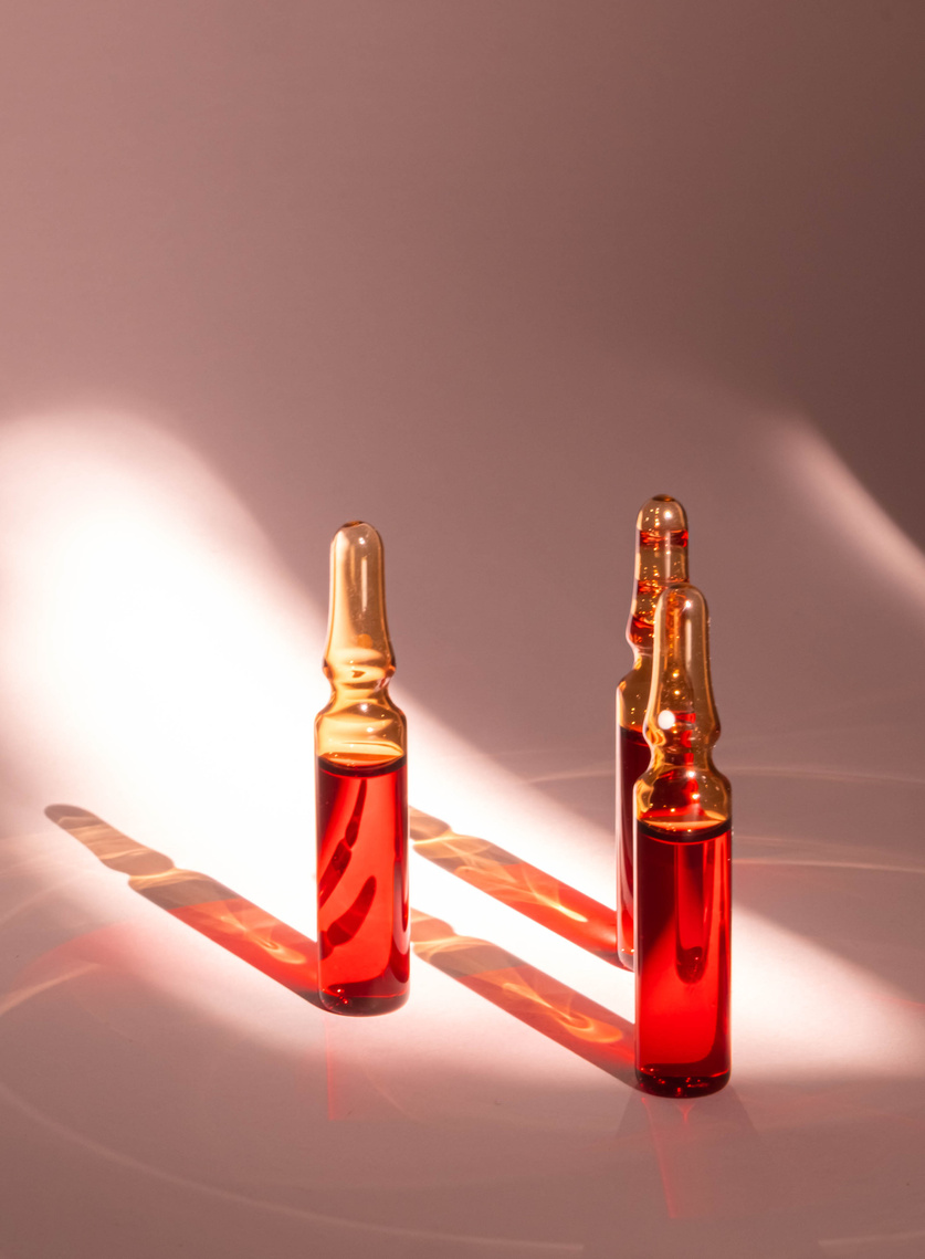 injections of B vitamins. Ampoules with red liquid. Beauty and health concept. Vertical photo